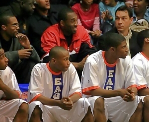 Kobe Bryant (center in red) and his then agent and now Los Angeles Lakers General Manager Rob Pelinka (to his left) watch the Eagles against St. Pius X in 2007. Eagles on the bench include (l-r) Allen Moorer, Steve Lattimore and Antonio Wilson. (Courtesy photo)