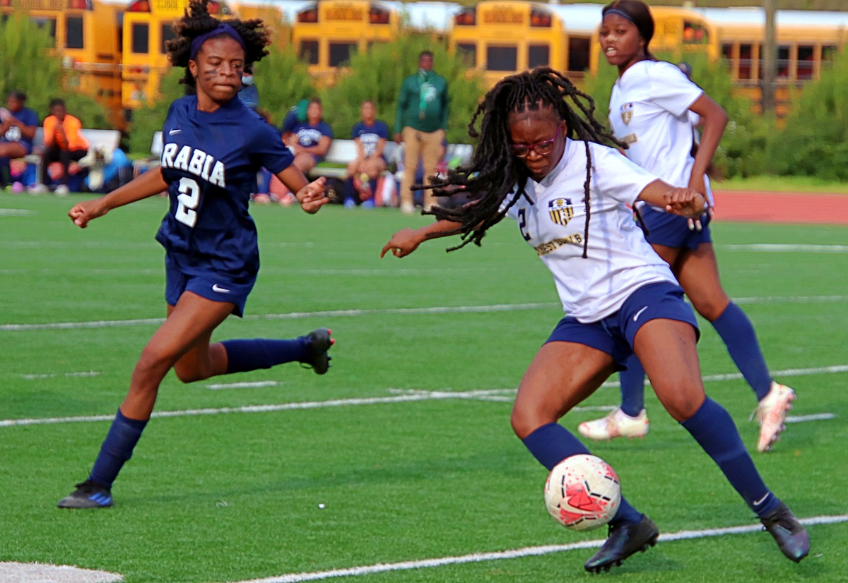 Southwest DeKalb's Bernice Kpotogbe (2 in white) turns up the field as Arabia Mountain's Ayana Peterson (2 in blue) comes up to defend. Arabia Mountain made a first half goal stand up in an 1-0 win. (Photo by Mark Brock)