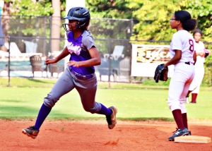 Miller Grove's Sydnee Newby (left) rounds second heading to third as Tucker second baseman Semara Brutus looks for a throw from the outfield. Newby ended up with a triple and later added a two-run, inside-the-park homerun in the Wolverines 17-0 win over the Tigers. (Photo by Mark Brock)