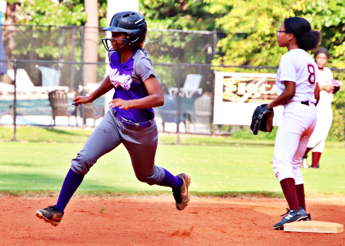 Miller Grove's Sydnee Newby (left) rounds second heading to third as Tucker second baseman Semara Brutus looks for a throw from the outfield. Newby ended up with a triple and later added a two-run, inside-the-park homerun in the Wolverines 17-0 win over the Tigers. (Photo by Mark Brock)