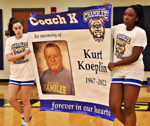 Chamblee Lady Bulldog basketball team members Alissa McKinzy (left) and Alana Azeta (right) present the banner going up in the Chamblee gym to honor the late Kurt Koeplin, the former girls' basketball coach and gold team coach at Chamblee who passed away suddenly in June. (Photo by Mark Brock)