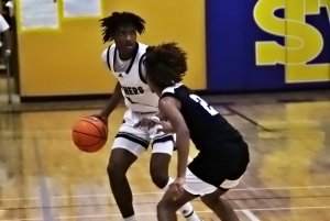 Southwest DeKalb's Xzaviah Traylor (with ball) examines the defense as Miller Grove's Javon Terrell comes out to cover during the Panthers 49-35 win over the Wolverines. (Photo by Mark Brock)