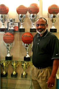 Columbia boys' basketball coach Dr. Phillip McCrary stands in front of his five championship trophies. His 32-year career now includes 700 career victories after the Eagles won the Dale Burns Classic in Freeport, Bahamas for the second consecutive season. (Photo by Mark Brock)