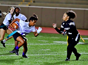 Lakeside's Leia Johnson (16) had a pair of pick-sixes in girls' flag football action against Lithonia and Cross Keys. Lithonia's Kila Phillips comes up to tackle Johnson on a punt return. (Photo by Mark Brock)
