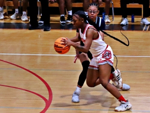 McNair's Kei'Asia Clayton (2) drives past Eagle's Landing Christian's Jazmine Lopez (5) on the way to a rally starting basket. The Lady Mustangs rallied from a 17-point deficit to win 42-40 and pick up their first state playoff bid since 2000. (Photo by Mark Brock)